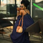 black woman wearing sunglasses sitting at table with purse