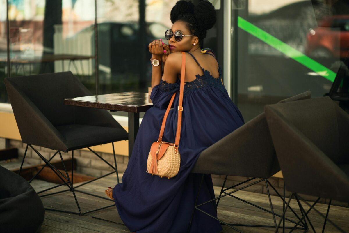 black woman wearing sunglasses sitting at table with purse