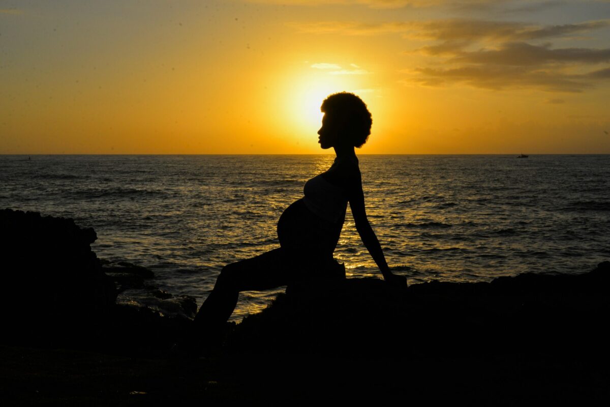 Pregnant woman sitting pn rock at beach