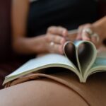 woman folding book pages into heart shape