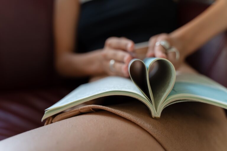 woman folding book pages into heart shape